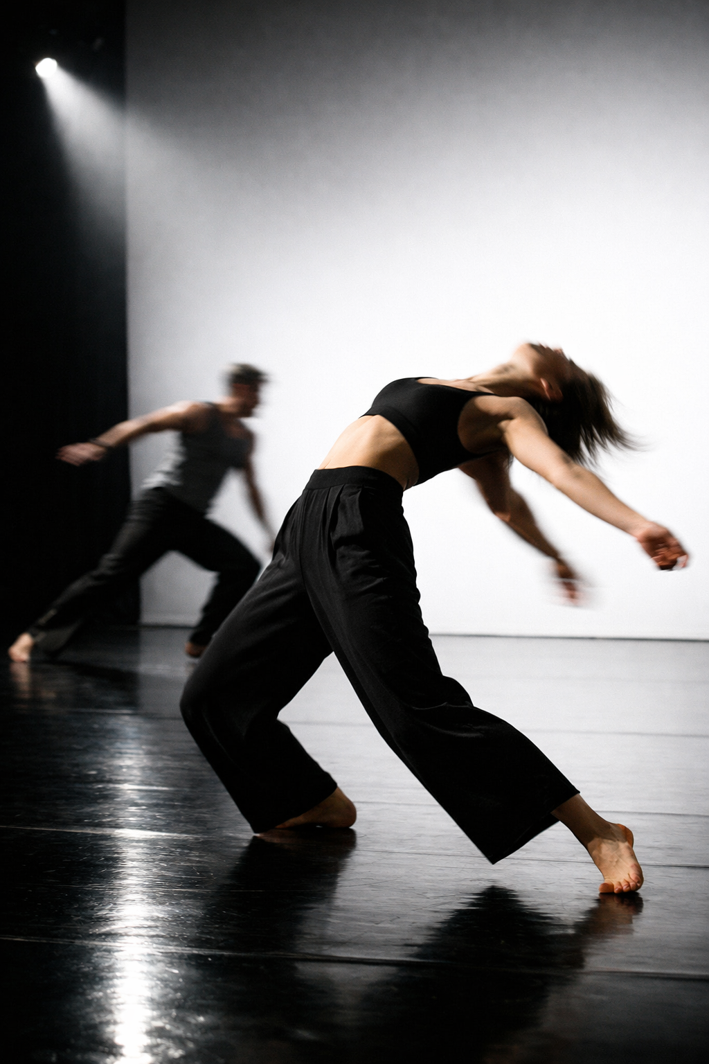 Contemporary dance duo in motion on a bare stage